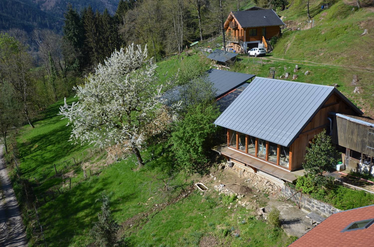 Vue aérienne du site au printemps : le fenil, l’écurie et l’atelier sur le versant